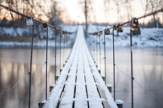 Fototapeta Locks on a rope bridge over frozen water