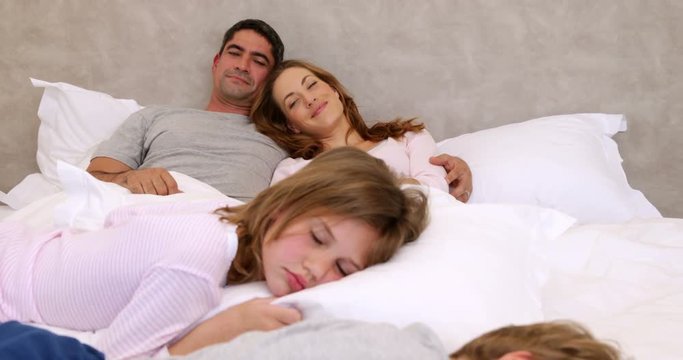 Cute parents and children lying on bed sleeping
