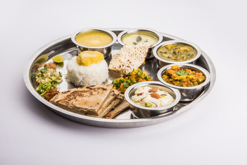 typical maharashtrian food served in a steal plate, marathi food includes kadhi and shrikhand, plain dal, spinach curry, aalu mutter, plain rice, papad, bhakri or bhakar or roti and variety of salad © StockImageFactory