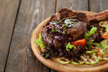 Bbq pork rib with grilled vegetables on cutting board, brown wooden background, free space