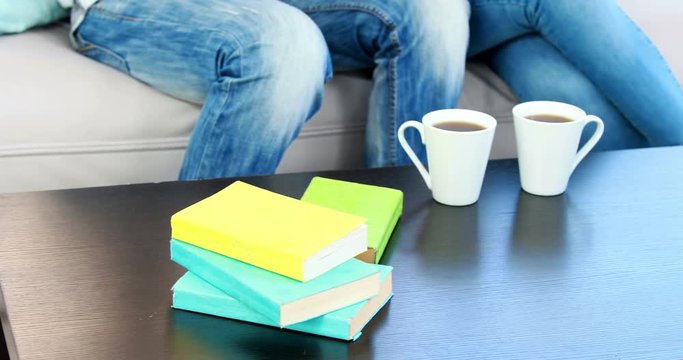 Table with books and coffee cups with a couple on the sofa