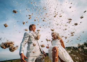 bride and groom are fighting pillows outdoor. Fun newlyweds during a photo shoot. Vintage style