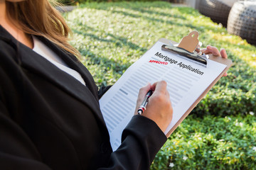 Businesswoman signing approved mortgage application in the garden