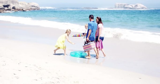 Young family walking together with picnic stuff on the beach