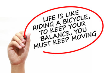Man writing LIFE IS LIKE RIDING A BICYCLE,TO KEEP YOUR BALANCE,YOU MUST KEEP MOVING with marker on transparent wipe board.