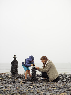 Sweden, Oland, Mother and daughter (4-5) building cairn on beach