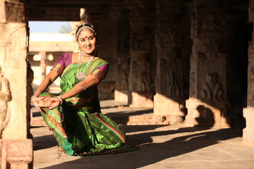 a kuchipudi dancer posing before a temple 