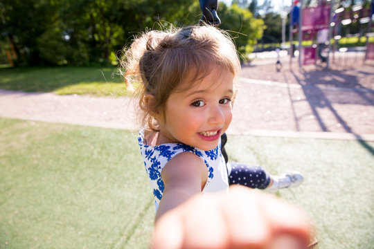 Beautiful Kid Taking Selfie In Green Summer Park, Laughing, Having Fun. Warm Sunny Weather, Healthy Child, Happiness, Freedom, Emotions. Cute Girl Reaching Hand To Camera. 