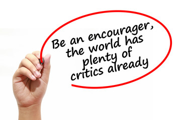 Man writing Be an encourager,the world has plenty of critics already with marker on transparent wipe board.