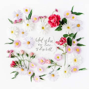 inspirational quote "what is done in love is done well" written in calligraphy style on paper with pink, red roses, chamomiles and leaves isolated on white background. Flat lay, top view