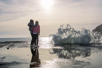 Amiche abbracciate al mare al tramonto che guardano un'onda antropomorfa minacciosa. La situazione...