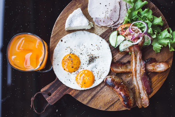 Breakfast with fried eggs, bacon and cheese camembert on wooden