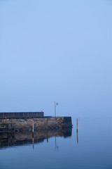 Obraz na płótnie Canvas habor stone pier mirroring in calm seas where the sky meets the sea in the horizon