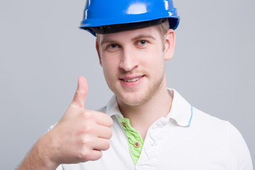 Junger Ingenieur mit Helm zeigt Daumen hoch
