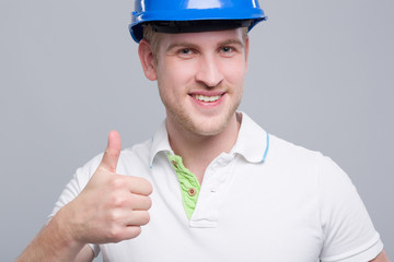 Junger Ingenieur mit Helm zeigt Daumen hoch