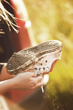 Sweden, Ostergotland, Hands of woman holding muddy canvas shoe