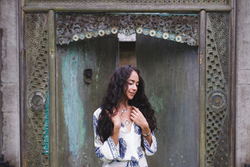 Young beautiful woman walking near old antique house in Bali sty