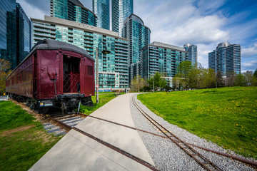 Railroad car at Roundhouse Park and modern buildings in downtown