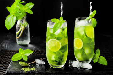 Matcha iced green tea with lime and fresh mint on black stone slate background. Super food drink