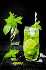 Matcha iced green tea with lime and fresh mint on black stone slate background. Super food drink