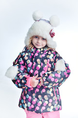Cute little funny child in colorful winter clothes having fun with snow, outdoors during snowfall. Active outdoors leisure with children in winter. Kid with  hat, hand gloves with stripes.