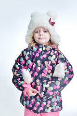 Cute little funny child in colorful winter clothes having fun with snow, outdoors during snowfall. Active outdoors leisure with children in winter. Kid with  hat, hand gloves with stripes.