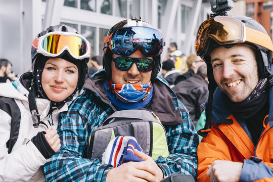 Three people, a young woman and two men in ski gear, in a row on a ski-ing holiday.