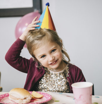 A Young Girl In A Party Hat At A Birthday Party.