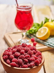 On wooden boards is ice cold raspberry cocktail glass with lemon . Alcohol country cocktail number hundred thirty with raspberry clay bowl on front background.