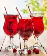 On wooden boards are ice cold beverage glasses with red raspberry lemon cocktail . Alcohol country cocktail beverage number hundred thirty three with raspberry . Cocktail on outdoor corporate.
