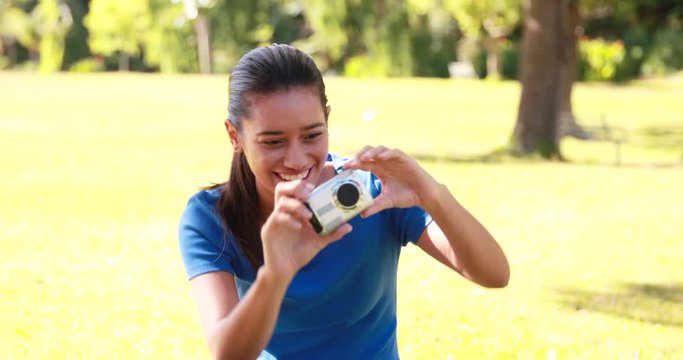 Smiling brunette taking pictures in the park on a sunny day