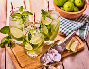 Alcohol drink. On wooden boards three glasses with straw alcohol drink and ice cubes. A drink number hundred thirteen cocktail mohito and scoop with glue bowl. Country life. Outdoor. Light background.