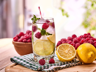 Alcohol drink. On wooden boards alcohol glass with straw and ice cubes. Drink number hundred twenty cocktail raspberry mojito with lime and mint leaf. Country life. Outdoor. Light background.