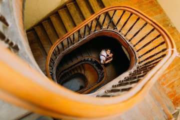 Fototapeta premium Gentle, sensual, sweet, passionate couple on the background of vintage marble stairs in Lviv. View from below