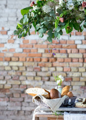 The table on which stands a vase of flowers and a basket of biscuits and bread and cheese
