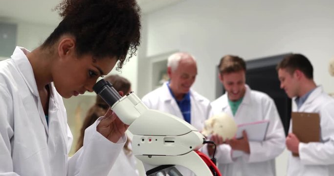 Pretty medical student looking through microscope in high quality 4k format