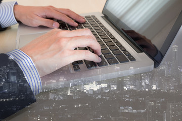businessman typing on keyboard laptop with cityscape background