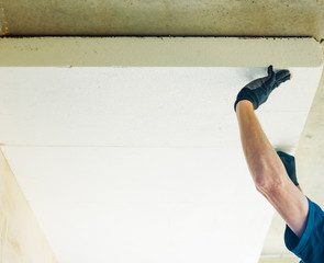man working with foam plastic at home ceiling renovation