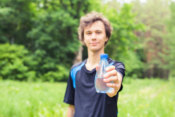 Sportsman with a bottle of water after running outdoors in park.