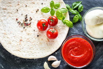 Pizza ingredients on the dark wooden background