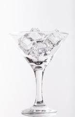 Ice cubes and martini glass on white background
