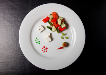 White plate with fresh salad on a black table or background
