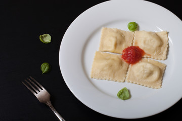 Russian ravioli - pelmeni with tomato sauce and basil on a white