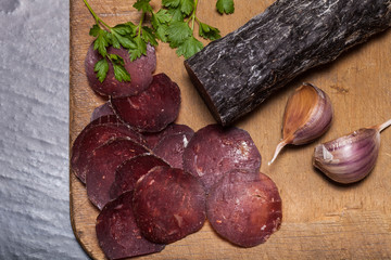 Sliced horse sausage, herbs and spices on cutting board