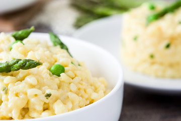 Risotto with asparagus, parsley and peas on a rustic wooden table

