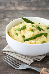Risotto with asparagus, parsley and peas on a rustic wooden table


