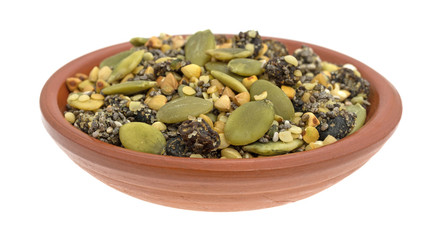 Chia cranberry and pumpkin seeds breakfast cereal in clay bowl on a white background.