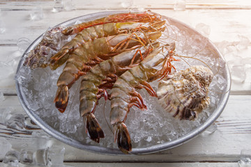 Shrimps with seashells on ice. Raw shrimps on ice cubes. Exotic seafood cooked at restaurant. Healthy and tasty food.