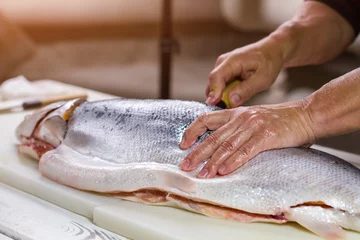 Crédence de cuisine en verre imprimé Poisson Male hand on raw fish. Big fish on cooking board. Fresh salmon for preparing makizushi. Gift of the sea.