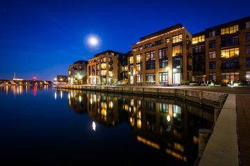 Fototapeta na wymiar The full moon over a waterfront apartment building in Fells Poin